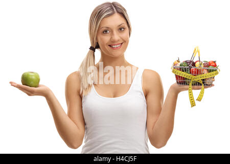 Femme joyeuse tenant une pomme et un petit panier avec une bande de mesure isolé sur fond blanc Banque D'Images