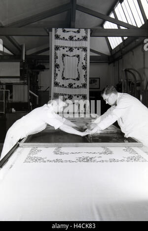 Zwei Mitarbeiter einer Textilfirma Stofbahn à Krefeld bedrucken eine mit einem Blumenmuster durch das Siebdruckverfahren, Deutschland 1930 er Jahre. Deux employés d'une entreprise textile à Krefeld sérigraphie d'un motif floral sur un panneau, Allemagne 1930 Banque D'Images