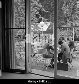 Männer und Frauen sitzen auf der Terrasse mit dem Außengastronomie und hören Orchester dans Wildbad im Schwarzwald zu, Deutschland 1930 er Jahre. Les hommes et les femmes assis dans une gastronomie plein air sur une terrasse et à l'orchestre listenig spa à Wildbad en Forêt Noire, Allemagne 1930. Banque D'Images