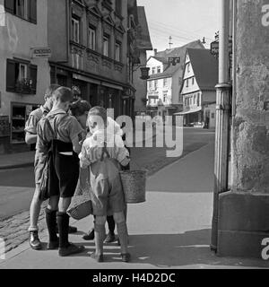 Vier Jungen in der Straße vor dem Kürschnerbetrieb Gemüsehaus und Karl Rometsch Bergkastelblick à Wildbad im Schwarzwald, Deutschland 1930er Jahre. Quatre garçons dans la rue en face de l'atelier de Karl Rometsch fourreur et Koehle's shop greengrocery à la ville de Wildbad en Forêt Noire, Allemagne 1930. Banque D'Images