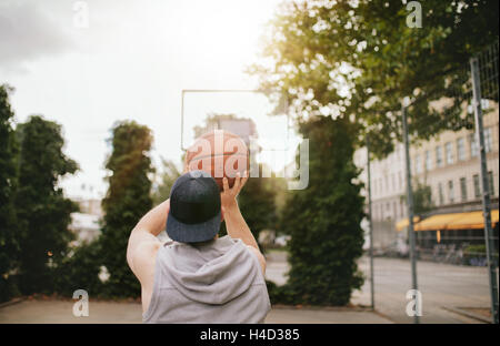 Vue arrière Vue d'un jeune homme jouant au basket-ball sur une cour. Streetball joueur lance panier. Banque D'Images