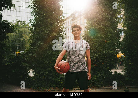 Portrait of young man holding a basket-ball sur le terrain extérieur de la cour. Portrait of two joueur de streetball looking at camera. Banque D'Images