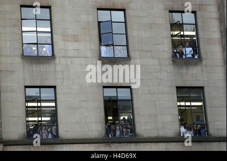 Les gens regardent par Windows comme ils regardent le duc et la duchesse de Cambridge, assister à une cérémonie de pavage en pierre récipiendaires de la Croix de Victoria au cénotaphe de Manchester au cours d'une journée de combats dans la région de Manchester. Banque D'Images