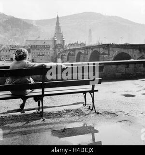 Eine junge Frau sitzt am gegenüberliegenden Ufer am Neckar Heidelberg von auf einer Bank, 1930er Jahre Deutschland. Une jeune femme assise sur la rive opposée de Heidelberg sur un banc sur la rivière Neckar, Allemagne 1930. Banque D'Images