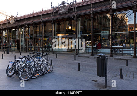 Mercado de San Miguel, extérieur botique bar à tapas et boulangerie, les personnes mangeant au comptoir à l'intérieur. 8 Service de location de vélos garés devant. Banque D'Images