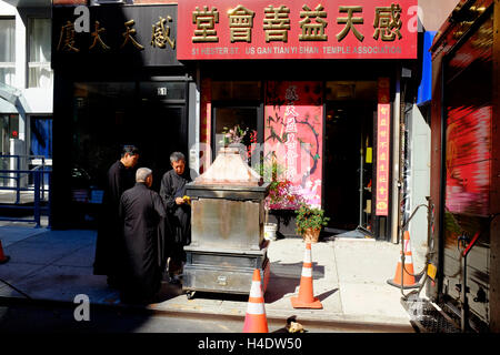 Les moines bouddhistes, l'argent de papier pour gravure joss est mort après une cérémonie à l'extérieur d'un temple à New York Chinatown.New York City, USA Banque D'Images