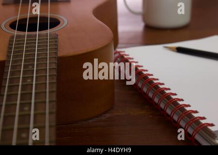 Tasse à café guitare Ukulele cahier et crayon sur table en bois close up Banque D'Images