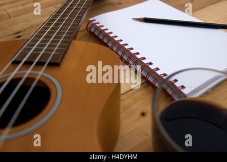 Tasse à café guitare Ukulele cahier et crayon sur table en bois close up Banque D'Images