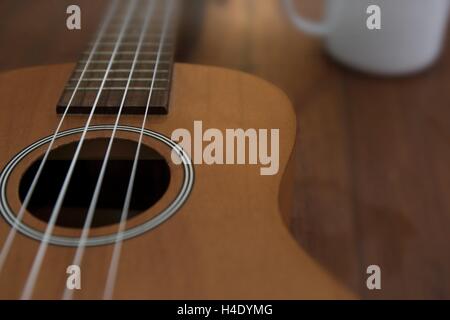 Ukulele guitare et tasse à café sur table en bois close up Banque D'Images