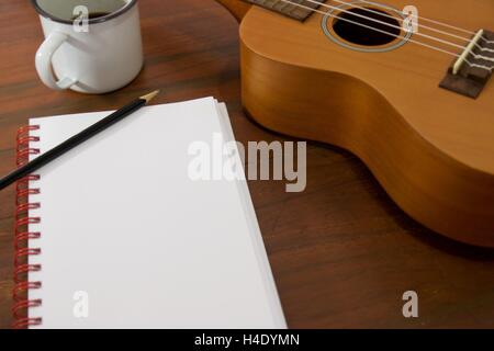 Tasse à café guitare Ukulele cahier et crayon sur table en bois close up Banque D'Images