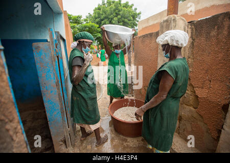 Les employés travaillent pour le beurre de karité de désabonnement manuellement à une installation de production du commerce équitable de Réo, Burkina Faso. Banque D'Images