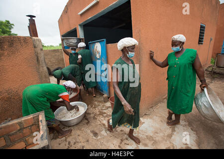 Les employés travaillent pour le beurre de karité de désabonnement manuellement à une installation de production du commerce équitable de Réo, Burkina Faso. Banque D'Images