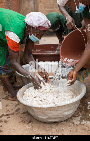 Les employés travaillent pour le beurre de karité de désabonnement manuellement à une installation de production du commerce équitable de Réo, Burkina Faso. Banque D'Images