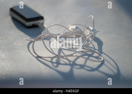 Lecteur mp3 stéréo personnel portant sur le cuir blanc éclairé par le soleil. Extrême artistique fond flou macro closeup Banque D'Images