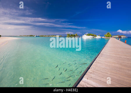 Pont menant à bungalow sur pilotis dans le lagon bleu autour de l'île tropicale Banque D'Images