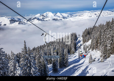 Skieurs sur télésiège appréciant la vue de foggy Télésieges à Kitzbuehel Alps ski resort, Autriche Banque D'Images