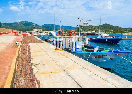 PORT DE PORTO GIUNCO, Sardaigne - 25 MAI 2014 : bateau de pêche et net sur la rive en Porto Giunco, port touristique de l'île de la Sardaigne, Italie. De nombreux touristes visitent l'île de la Sardaigne dans l'heure d'été. Banque D'Images