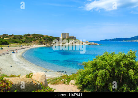 Plage avec la mer d'azur et château en arrière-plan, près de Porto Giunco, port de l'île de la Sardaigne, Italie Banque D'Images