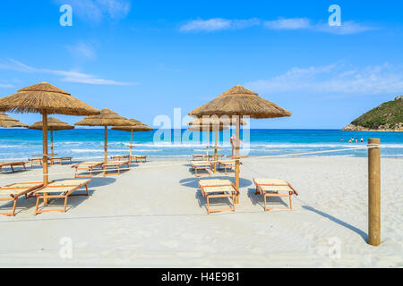 Des chaises longues avec parasols sur la plage de sable blanc dans la baie de Porto Giunco, Sardaigne, île, Italie Banque D'Images