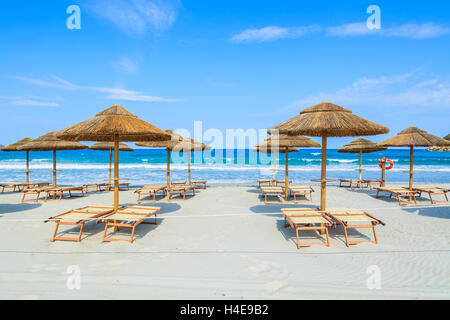 Des chaises longues avec parasols sur la plage de sable blanc dans la baie de Porto Giunco, Sardaigne, île, Italie Banque D'Images