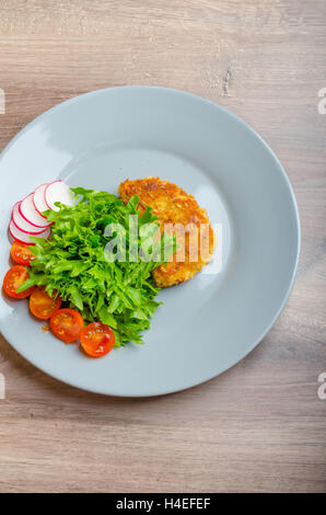 Côtelettes de porc pané au parmesan, la laitue et les radis et tomates cerises Banque D'Images