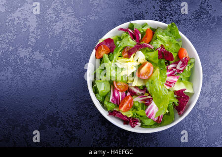 Salade d'endives fraîches avec tomates cerises et sur la plaque noire coin, verser de l'huile d'olive Banque D'Images