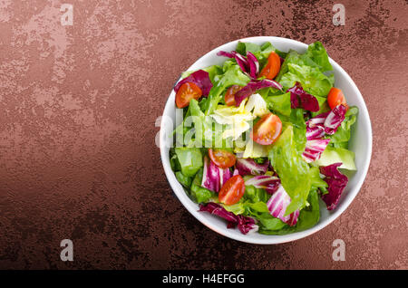 Salade d'endives fraîches avec tomates cerises et sur la plaque noire coin, verser de l'huile d'olive Banque D'Images