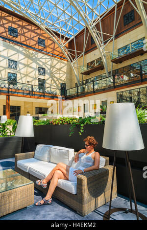ARLAMOW HOTEL, POLOGNE - Août 3, 2014 : Jeune femme assise sur un canapé dans le magnifique lobby restaurant à Arlamow Hôtel. Ce complexe de luxe est situé dans la région de Bieszczady. Banque D'Images