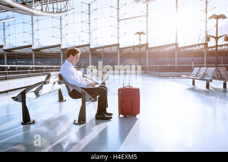 Young adult using laptop in airport lounge Banque D'Images