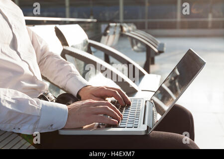 Businessman in airport lounge attente typing on laptop Banque D'Images