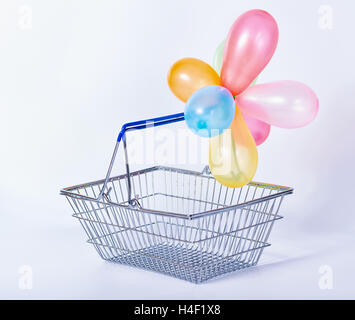 Concept de vacances ou vente de fête panier métal vide avec des ballons colorés sur set background, Close up Banque D'Images