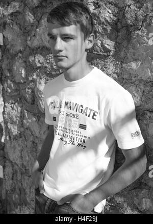 Le noir et blanc portrait of young man leaning against stone wall Banque D'Images