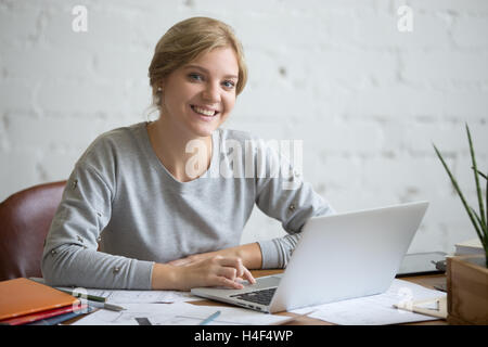 Portrait of a smiling student girl at desk with laptop Banque D'Images