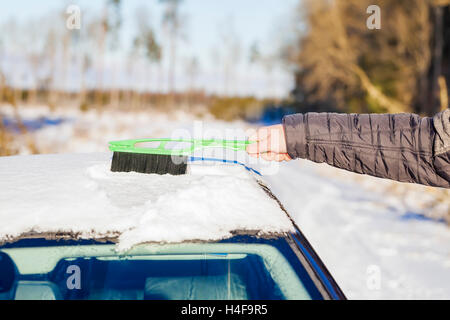 L'homme avec la brosse de nettoyage voiture hors de la neige Banque D'Images