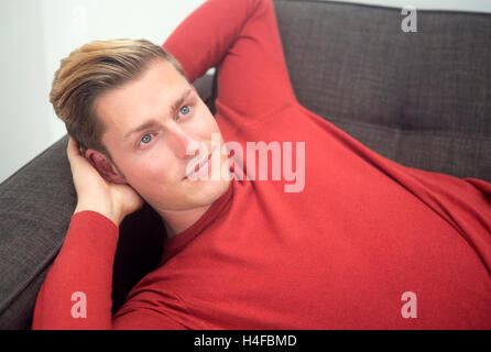 Portrait of handsome man blonde lying on couch Banque D'Images