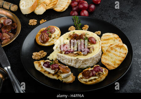 Fromage Brie gratiné au noix et raisins, baguette croustillante et savoureuse et herbes bio, réduction de sucre, de noix et de vinaigre balsamique Banque D'Images