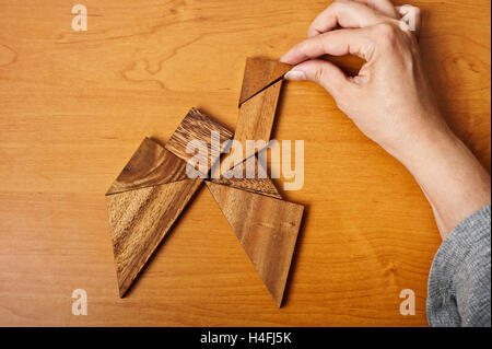 Mains d'une femme jouant le jeu de Tangram Banque D'Images