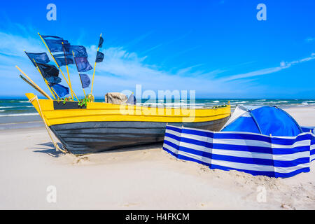 Bateau de pêche colorés et coupe-vent bleu avec tente sur la plage de sable de la mer Baltique, Pologne Banque D'Images