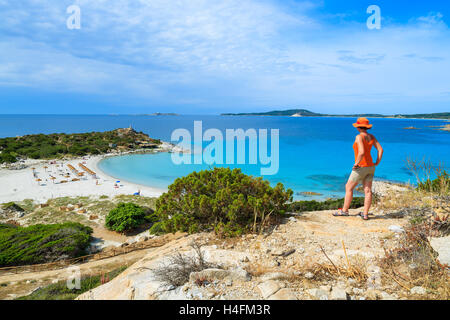 Jeune femme debout sur touristiques crock élevé avec vue sur la magnifique baie avec plage de sable de Punta Molentis, Sardaigne, île, Italie Banque D'Images