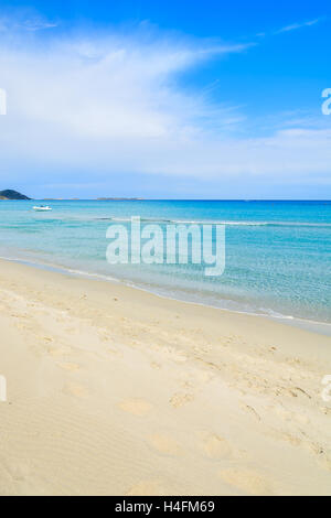 Plage de sable blanc et le bateau blanc à distance sur la mer turquoise de l'eau plage de Porto Giunco, Sardaigne, île, Italie Banque D'Images