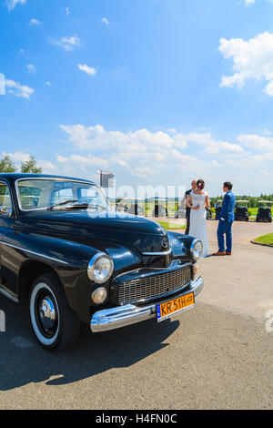 PACZULTOWICE GOLF CLUB, POLOGNE - Aug 9, 2014 : vieille voiture classique parcs sur rue dans Paczultowice Golf Club avec mariés couple en arrière-plan juste avant la cérémonie de désherbage. Banque D'Images