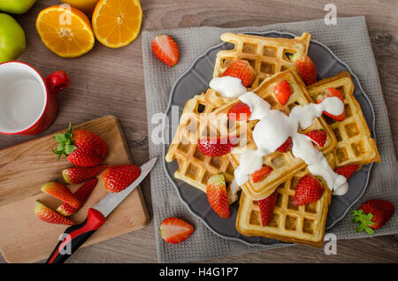 Gaufres maison au sirop d'érable et fraises, garni de crème et de chocolat, la boisson fraîche orange Banque D'Images