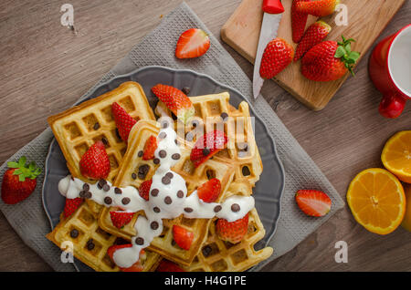 Gaufres maison au sirop d'érable et fraises, garni de crème et de chocolat, la boisson fraîche orange Banque D'Images