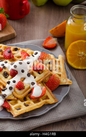 Gaufres maison au sirop d'érable et fraises, garni de crème et de chocolat, la boisson fraîche orange Banque D'Images