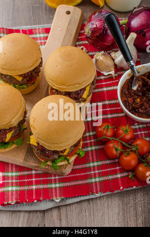 Curseurs de boeuf avec sauce barbecue maison, cheddar, tomates cerises et microgreens Banque D'Images