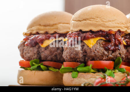 Curseurs de boeuf avec sauce barbecue maison, cheddar, tomates cerises et microgreens Banque D'Images