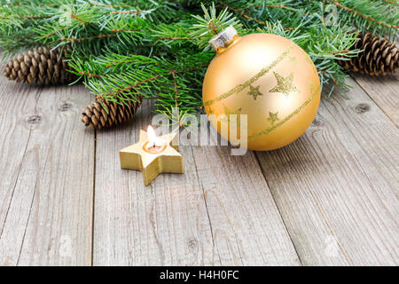 Bougie brûlante et d'or Boule de Noël avec des branches de sapin sur fond de bois Banque D'Images