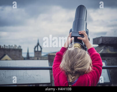 Petite fille qui s'étend à d'être capable de regarder à travers le télescope sur la plate-forme panoramique au sommet de Camera Obscura à Édimbourg Banque D'Images