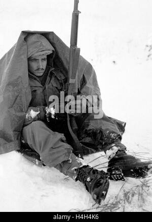 Soldat américain PFC. Preston McKnight, avec le 19ème régiment d'infanterie, utilise son poncho pour se protéger contre les morsures du vent et du froid au cours de la guerre de Corée le 10 janvier 1951, en Corée. Yoju dans Banque D'Images