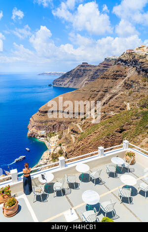 Jolie femme non identifiés en robe élégante debout sur une terrasse et regarder la mer et la caldeira, magnifique villa Firostefani Banque D'Images